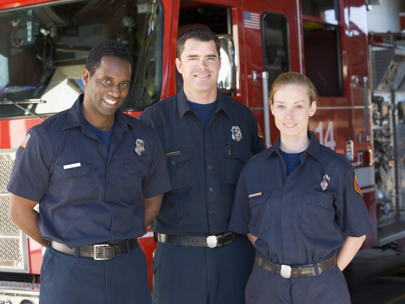Firefighters standing together in front of a fire engine